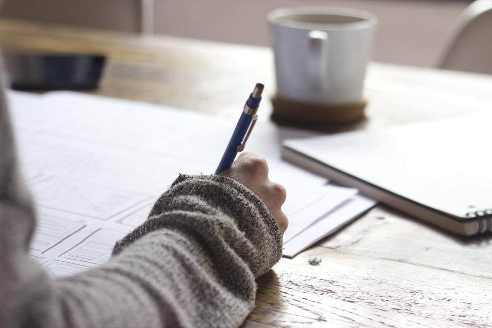 A student planning at a desk with a notepad and pen