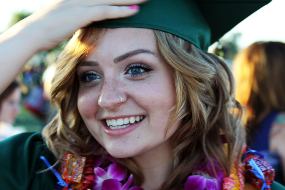 A smiling graduate lifting their cap on results day